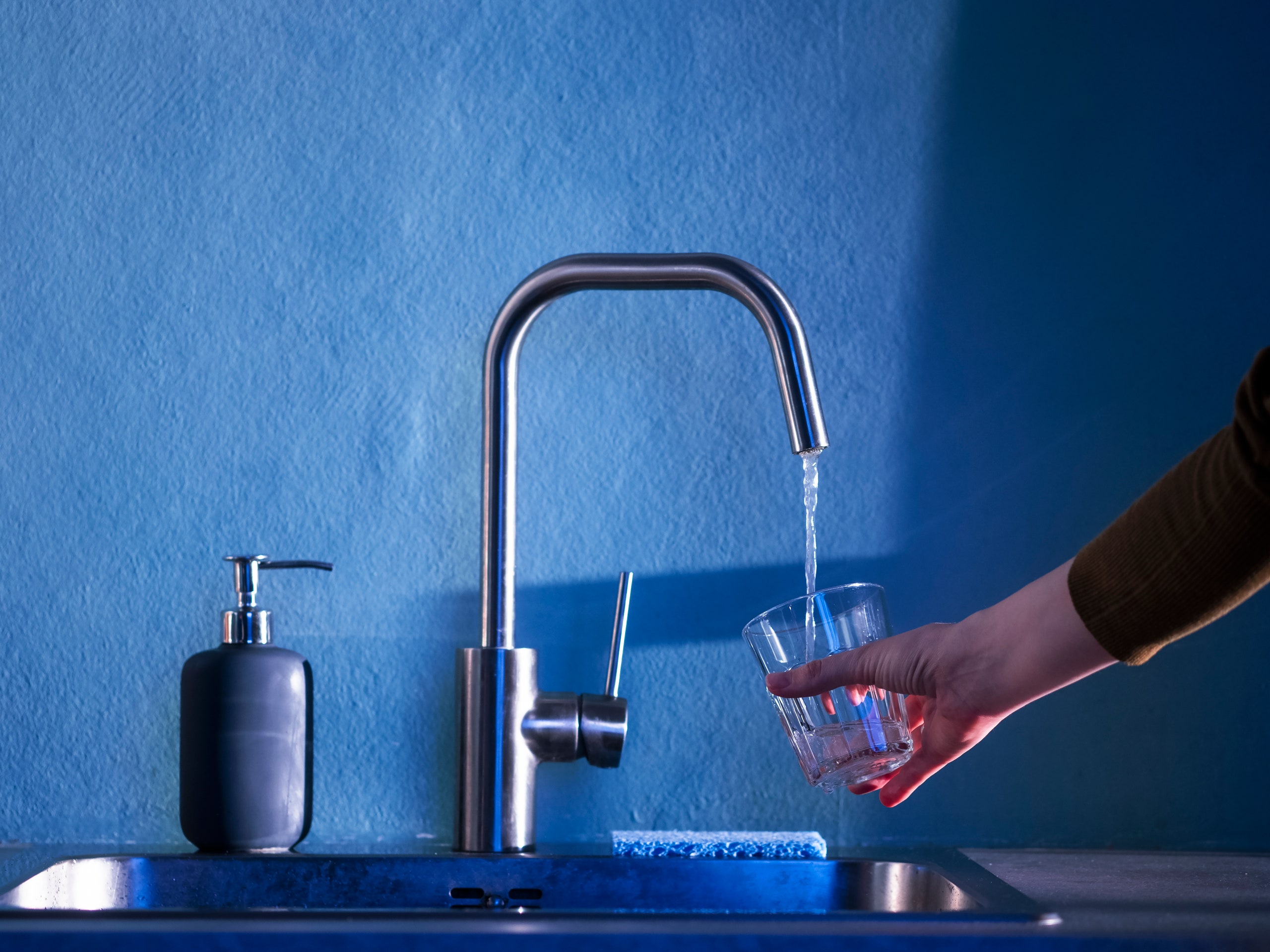 Person filling water glass at sink
